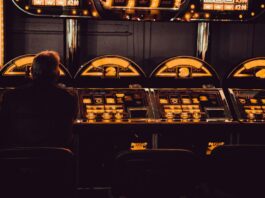 Ein Mann sitzt in dunkler Umgebung an einem Spielautomaten