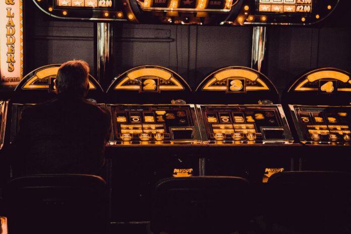 Ein Mann sitzt in dunkler Umgebung an einem Spielautomaten