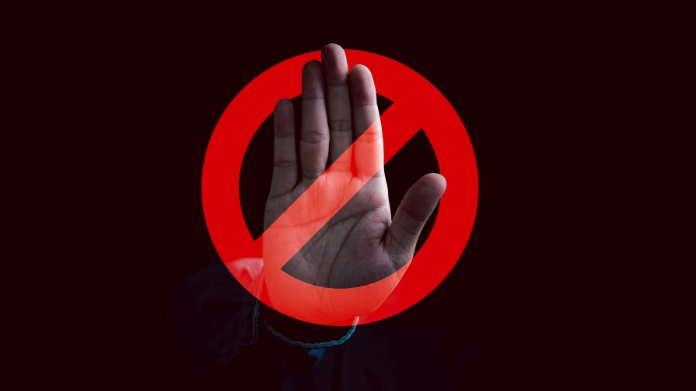 En uppsträckt hand bakom en röd stoppsymbol signalerar avvisande