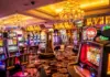 Färgglada spelautomater och blinkande lampor i ett casino med lyxiga mattor och taklampor.