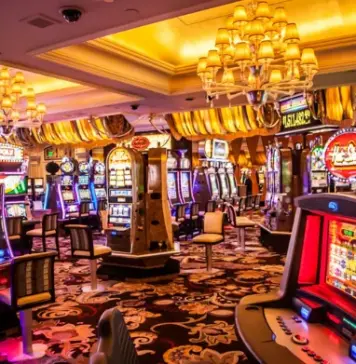 Färgglada spelautomater och blinkande lampor i ett casino med lyxiga mattor och taklampor.