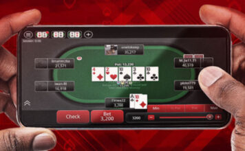 Två händer håller en mobil med ett pokerbord på skärmen och flera spelare runt bordet.