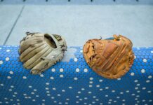 A pair of baseball gloves resting on a blue and white rail