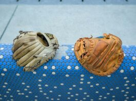 A pair of baseball gloves resting on a blue and white rail