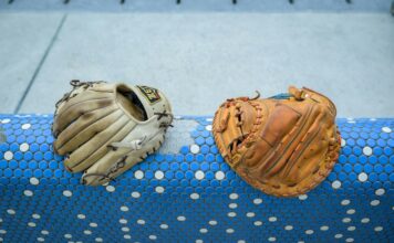 A pair of baseball gloves resting on a blue and white rail