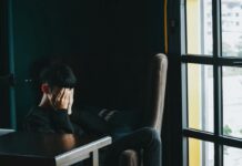 a person sitting in an office with their hands over their face