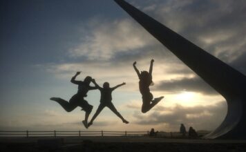 a trio of shadows jumping in the air in a park