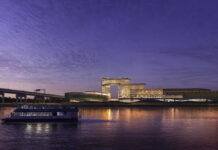 Nighttime rendering of Bally’s proposed Bronx casino resort viewed from the East River with ferry in foreground.