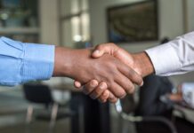 Two people shaking hands in a professional setting.