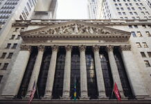 Facade of the New York Stock Exchange with flags and columns.