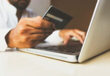 Person holding a credit card while using a laptop