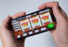 Person playing an online slot machine game on a smartphone, representing sweepstakes casino gameplay.